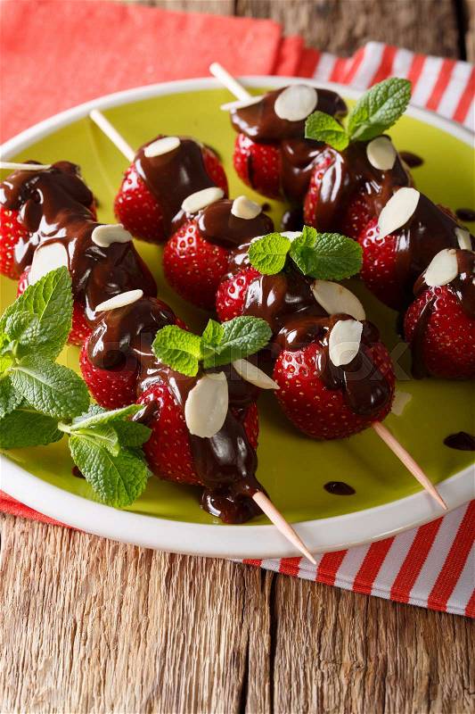 Ripe strawberries decorated with chocolate, mint and almonds close-up on a plate. vertical , stock photo