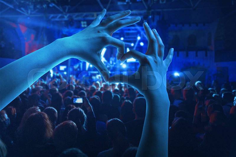 The silhouettes of concert crowd in front of bright stage lights. Concert of an abstract rock band, stock photo