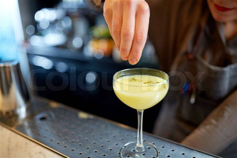 Alcohol drinks, people and luxury concept - woman bartender with glass preparing cocktail at bar, stock photo