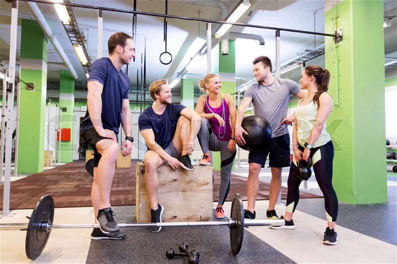 Fitness, sport and healthy lifestyle concept - group of happy people with different sports equipment talking in gym, stock photo