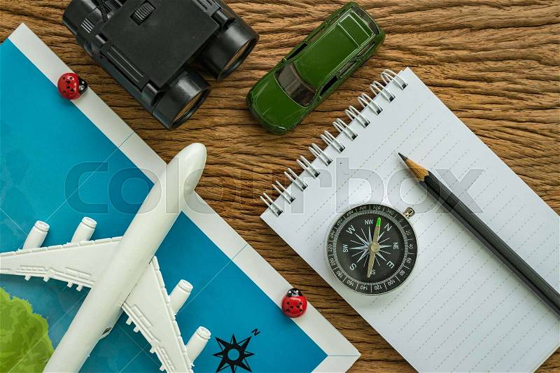 Travel planning road trip concept with airplane, passport, compass, binoculars, pencil, paper note and miniature car on wood table, stock photo