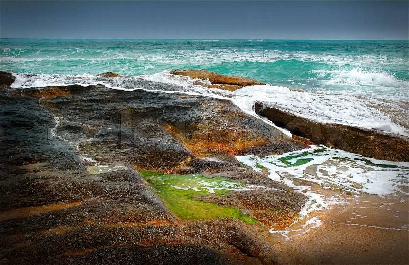 Water spilling over the rocks on the coast - Thailand, stock photo