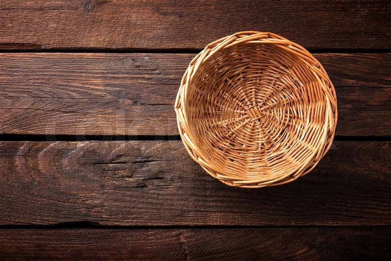 Empty wicker basket on a wooden background, top view, stock photo