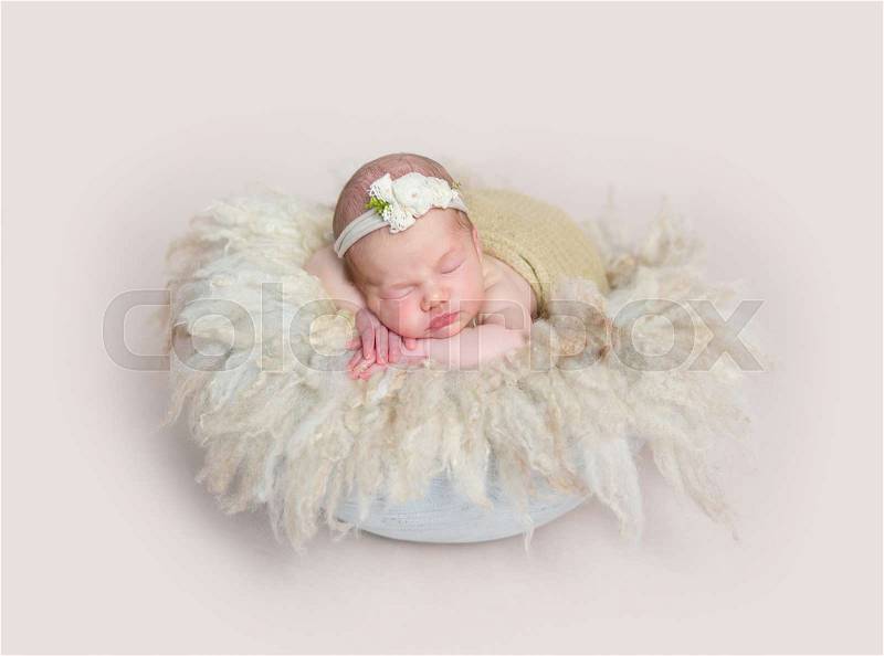 Adorable girl sleeping on huge soft fury pillow, wearing cute little headband, stock photo
