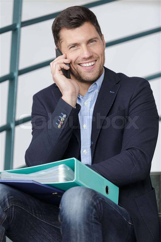 Man speaking on the phone with folder of documents, stock photo