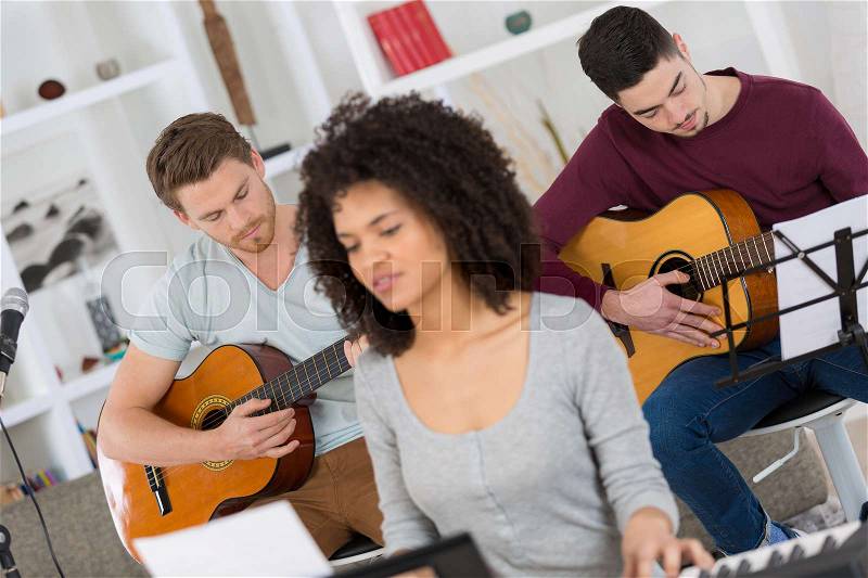 Friends playing music indoors, stock photo