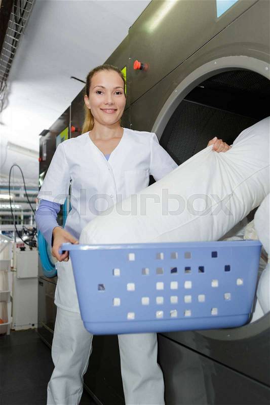 Smily woman working at an industrial laundry, stock photo