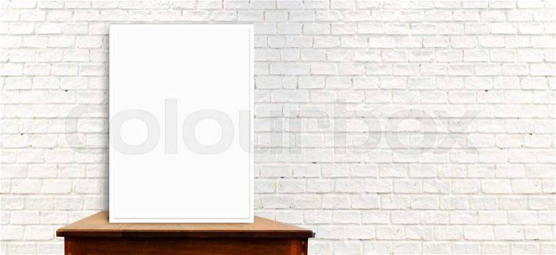 White frame mock up on the wood table at long white brick wall,leave space to add text content, stock photo