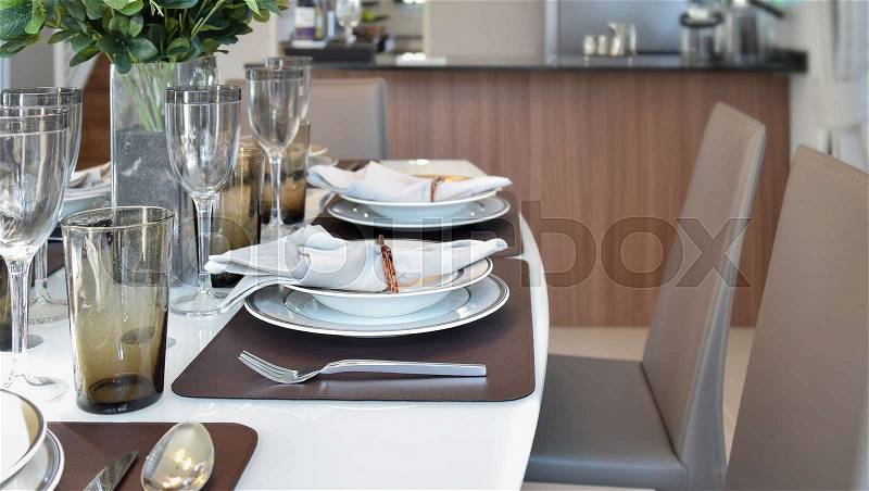 Elegant table set in modern style dining room interior, stock photo