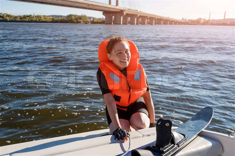 Young fit woman ready to ride water skis siting on the boat closeup. Athlete water skiing and having fun. Living a healthy lifestyle and staying active. Water sports theme, stock photo