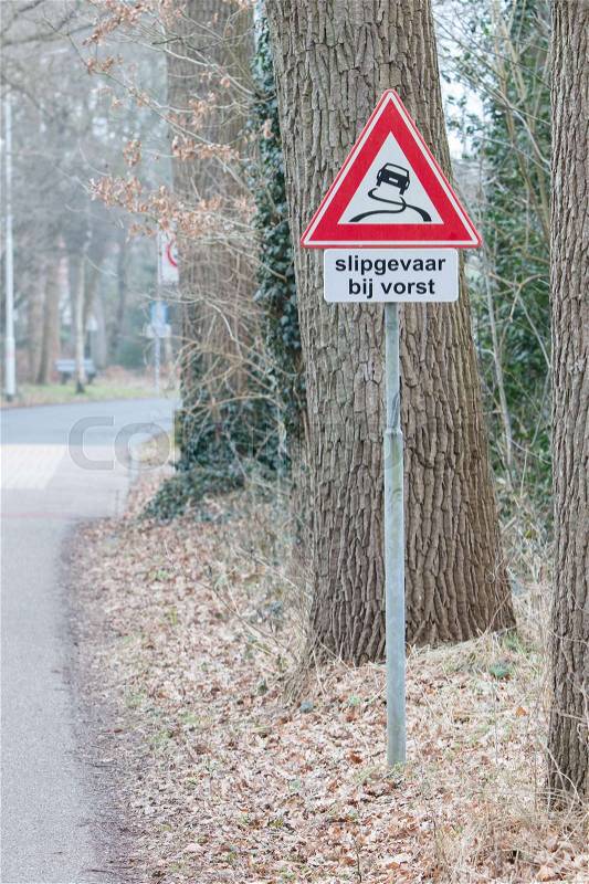 Road sign warning against slippery road due to snow ice (dutch), stock photo