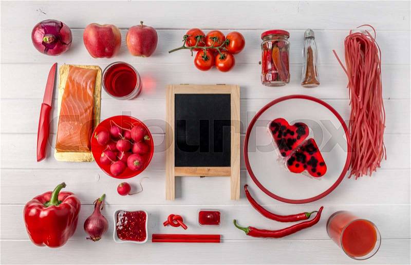 Collection of red food organized on white table, black chalkboard in center, topview, stock photo