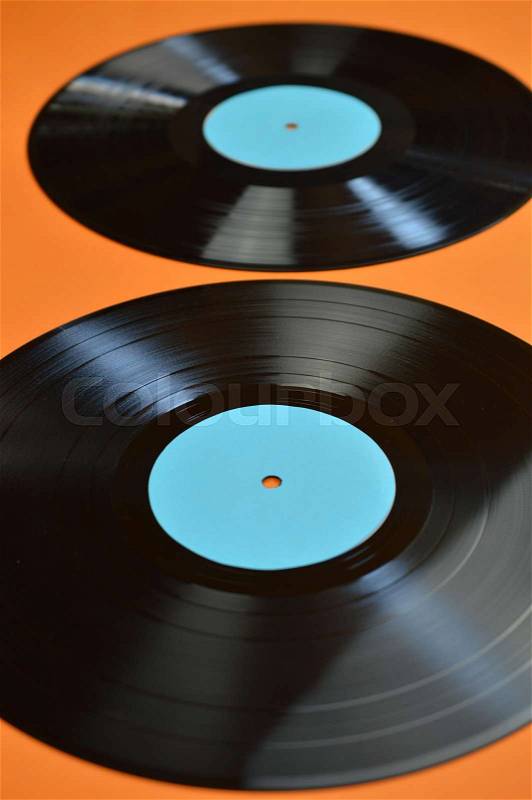 Zwei alte schwarze Langspiel Schallplatten aus Vinyl mit türkisfarbenem Etikett auf orangenem Hintergrund, stock photo