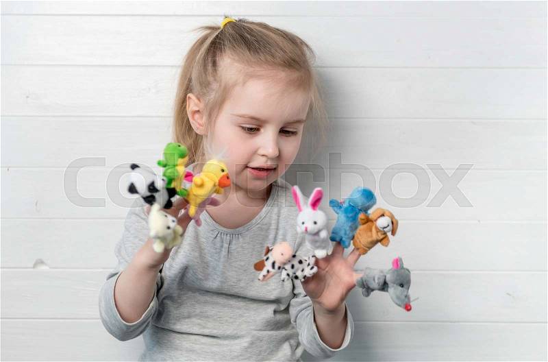 Lovely small girl with doll puppets on her hands, smiling and playing, stock photo