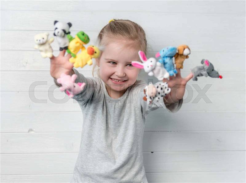 Lovely small girl with doll puppets on her hands, smiling and playing, stock photo