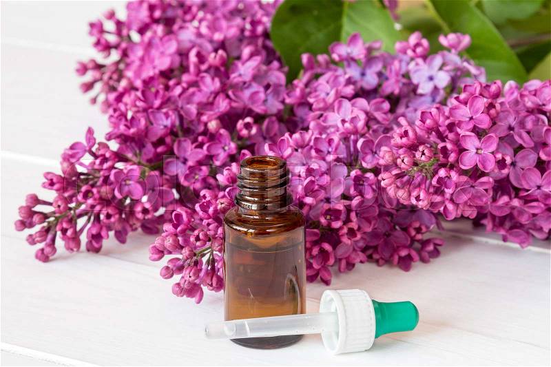 Bottle with aroma oil and lilac flowers on white background, stock photo