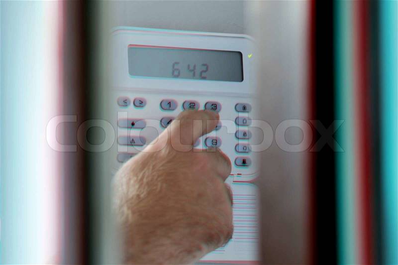 This photograph represent a human hand arming a burglar alarm system The view is similar as a a spy view this situation, stock photo