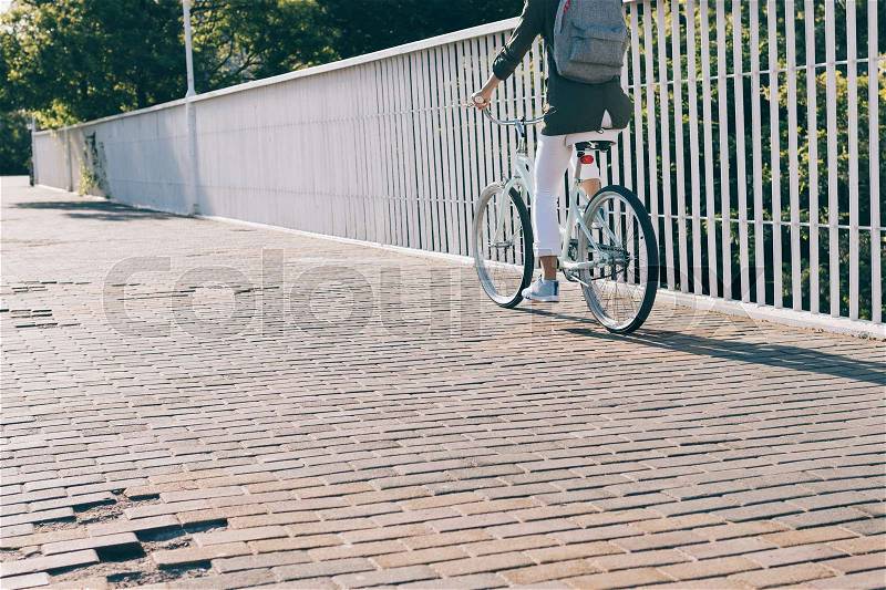 Slender woman riding a city bike on a sunny morning, the view from the back, stock photo