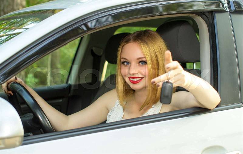 Beautiful girl sells car, offers you the keys, stock photo