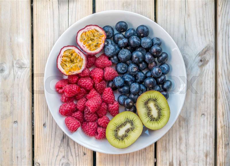 Overhead view of Blueberry, raspberry, kiwi, passion fruit on plate, stock photo