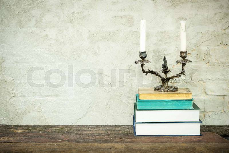 Colorful composition with vintage old books,diary on wooden deck table and beige concrete background. Books stacking with classic candlestick on top. Back to school. Copy Space. Education background, stock photo