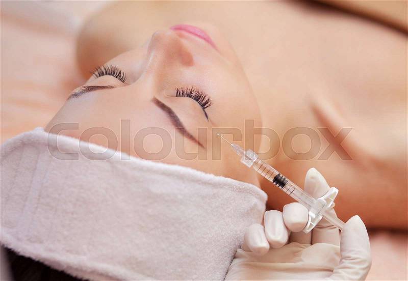 The doctor cosmetologist makes the Botulinotoxin injection procedure for tightening and smoothing wrinkles on the face skin of a beautiful, young woman in a beauty salon.Cosmetology skin care, stock photo