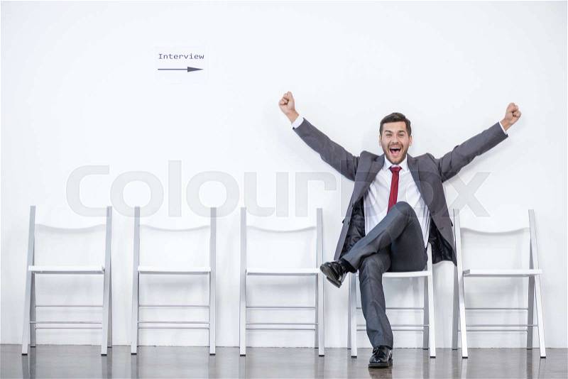 Excited businessman sitting and waiting for interview in office, business concept, stock photo