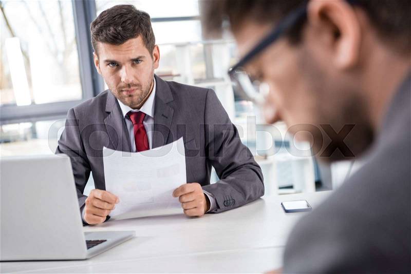 Unsatisfied boss looking at upset colleague at business meeting , stock photo