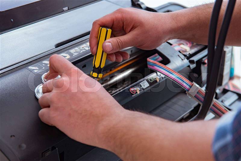Repairman repairing broken color printer, stock photo