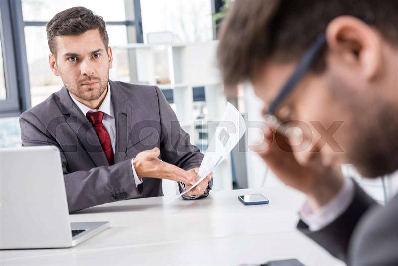 Unsatisfied boss looking at upset colleague at business meeting , stock photo