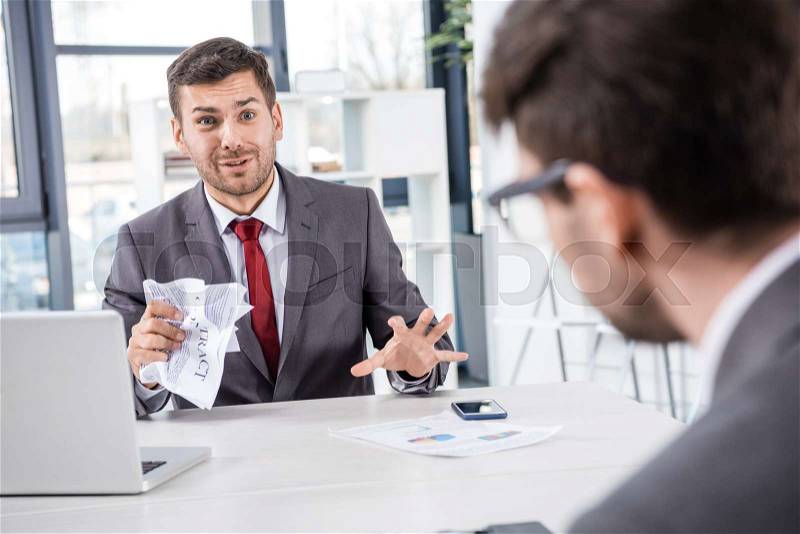 Stessed boss looking at upset colleague at business meeting, stock photo