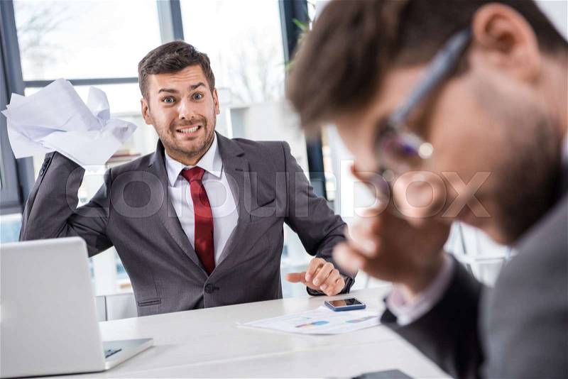 Angry boss throwing papers at upset colleague at business meeting, stock photo