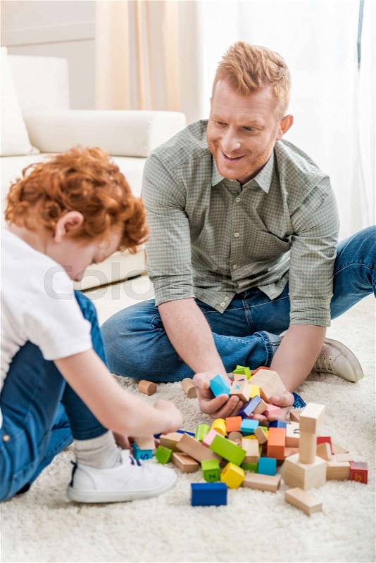 Father and adorable son playing with constructor on floor at home, family fun at home concept, stock photo