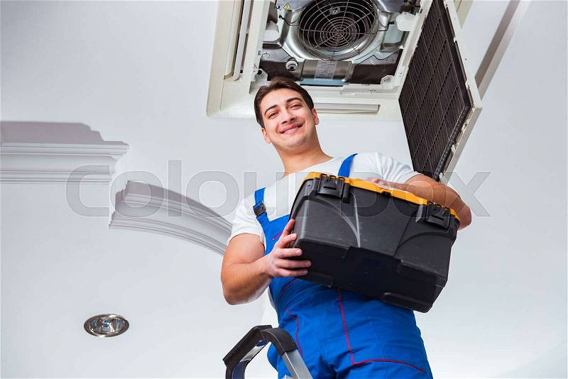 Worker repairing ceiling air conditioning unit, stock photo