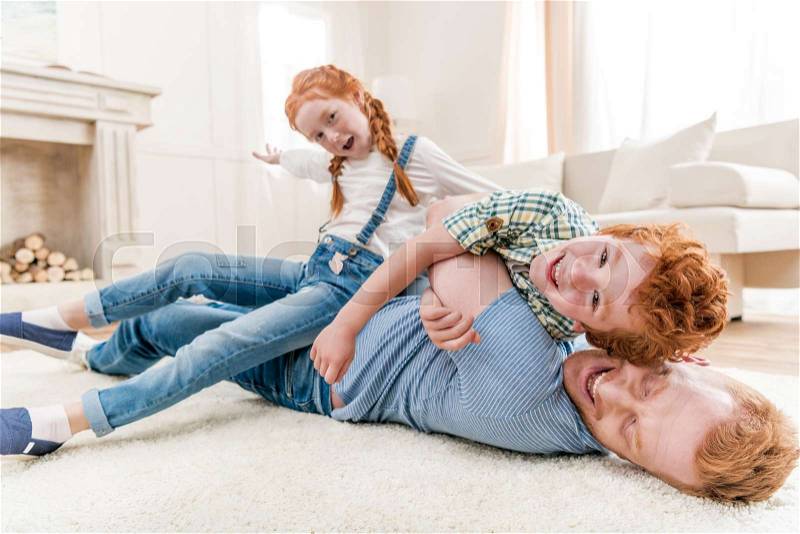 Happy father playing with daughter and son at home, family fun at home concept, stock photo