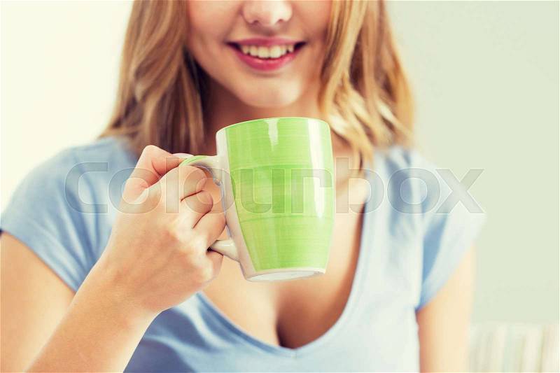 People and drinks concept - close up of happy woman or teen girl drinking tea from cup, stock photo