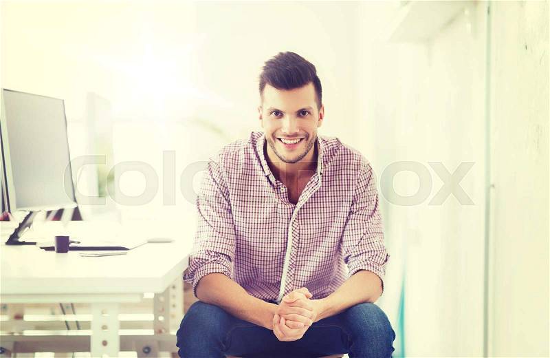 Business, technology, education and people concept - happy young creative man or student with computer at office, stock photo