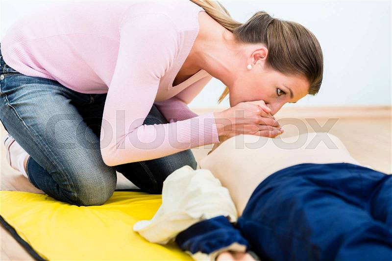 Woman training mouth-to-mouth breath donation on Rescue-Annie in first aid course, stock photo