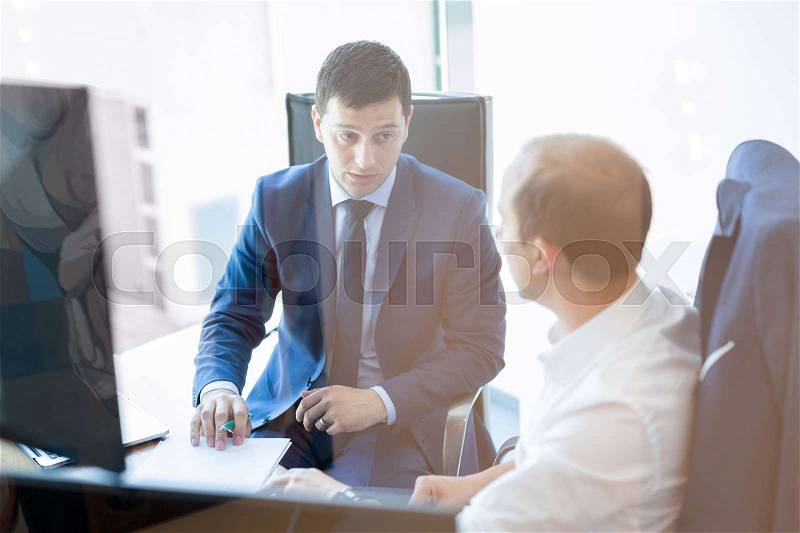 Image of two corporate businessmen discussing a bisiness problem at meeting in modern trading office. Businesspeople sitting at the boardroom and discussing business-plan, stock photo