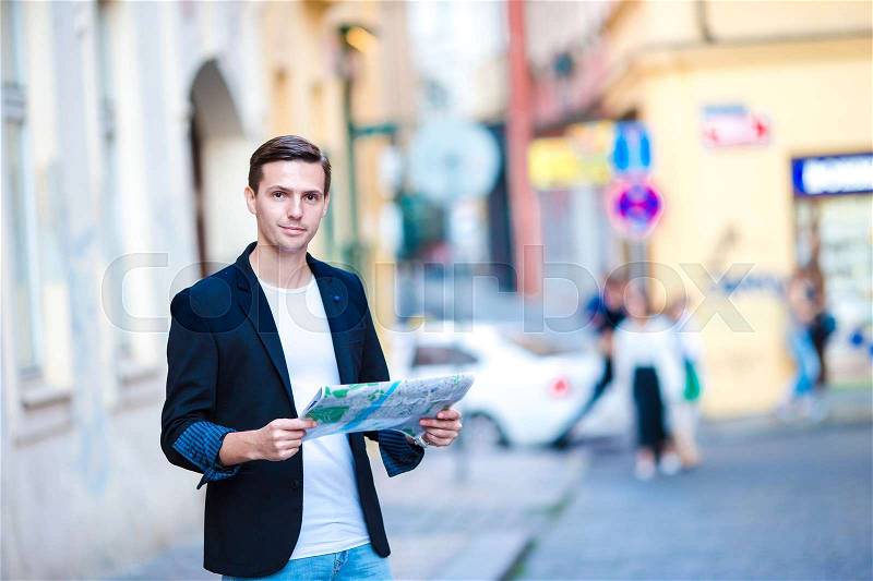 Man tourist with a city map and backpack in Europe street. Caucasian boy looking with map of European city, stock photo