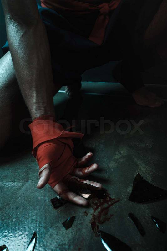 Muay Thai athlete holding glass shatters indoors, fight club concept, stock photo