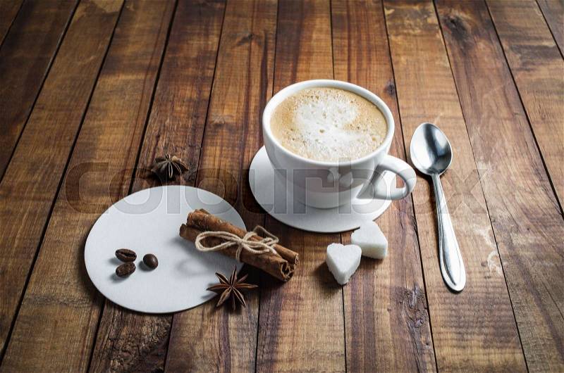 Coffee and spices. Coffee cup, cinnamon sticks, coffee beans, anise, sugar, spoon and coasters on vintage wood background, stock photo