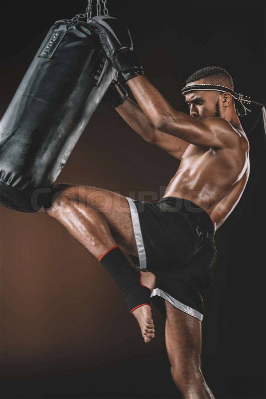 Side view of muay thai fighter training with punching bag, action sport concept, stock photo