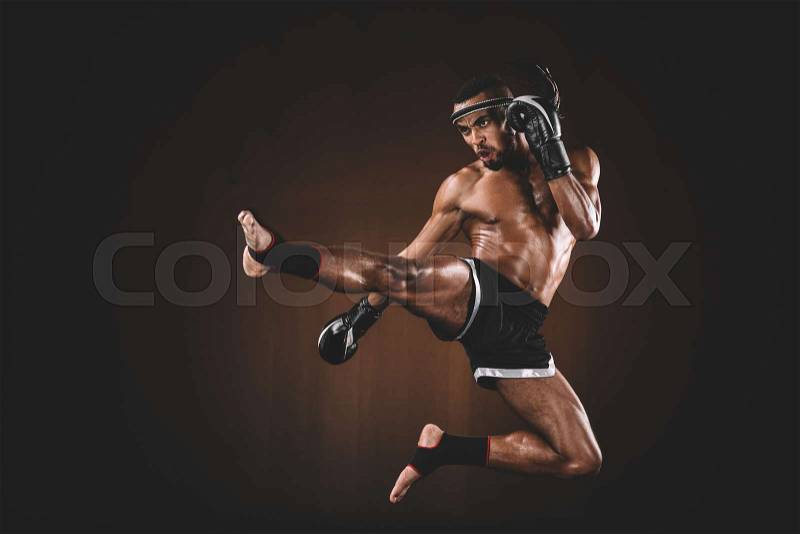 Side view of angry trainign muay thai fighter in boxing gloves, action sport concept, stock photo