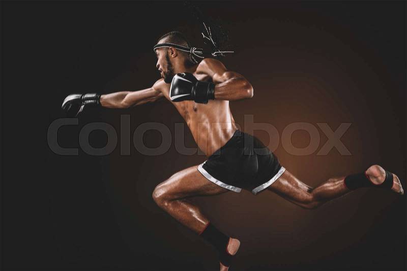Side view of muay thai fighter in boxing gloves practicing punch, action sport concept, stock photo