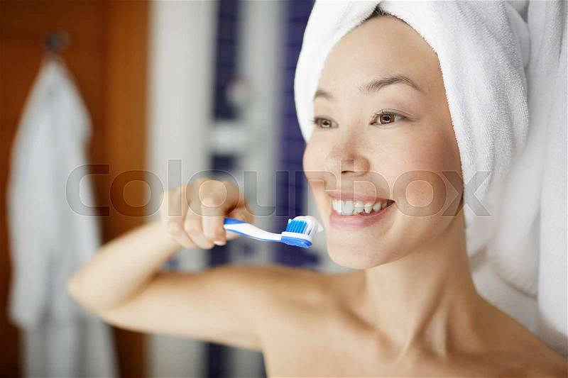 Portrait of smiling young woman brushing white teeth in shower during morning  beauty treatment routine, stock photo