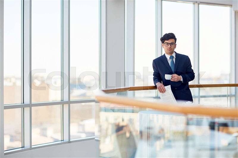 Serious employer with cup of coffee and newspaper, stock photo