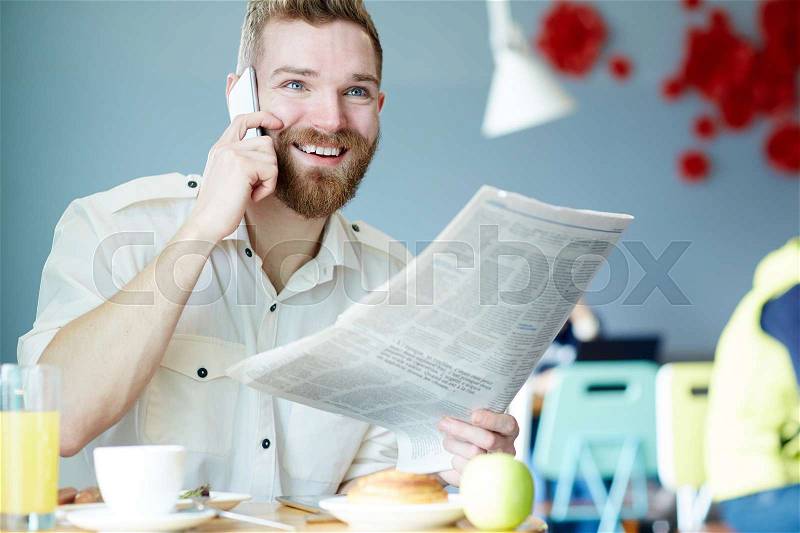 Calling businessman with newspaper having lunch break, stock photo