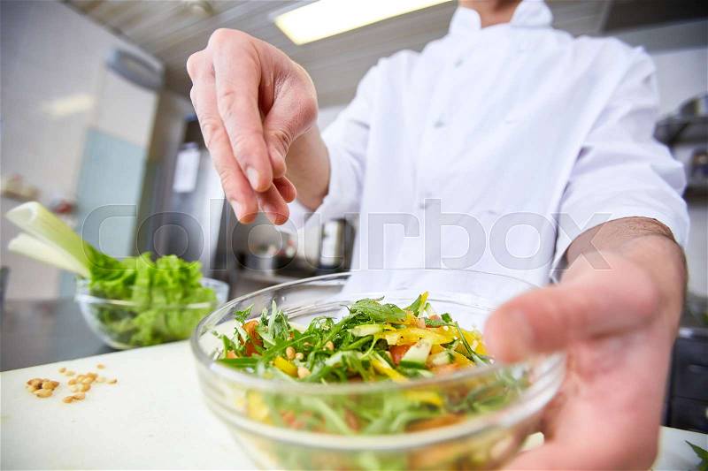 Chef seasoning salad by ground nutmeg, stock photo