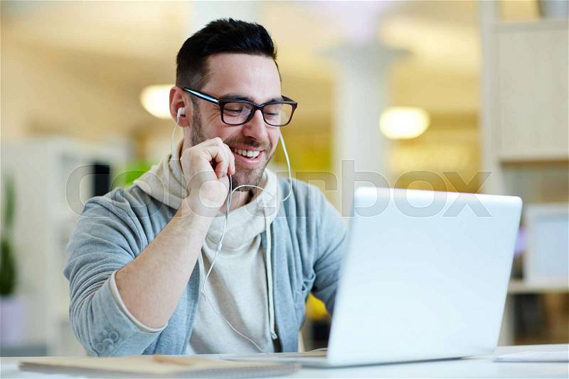 Businessman with earphones enjoying break in front of laptop, stock photo